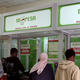 A man leaves an M-PESA booth after a money transaction in Nairobi May 12, 2009. Teaming up with Kenya Commercial Bank to let phone users who do not have bank accounts send each other money, M-PESA, the virtual cash network, hit on a formula that has attracted 6.5 million customers, or one in six Kenyans, in just over two years. Picture taken May 12, 2009.